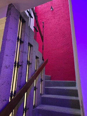 A staircase with a red wall and a purple-lit handrail. - Casa Puerto Siete8 (Mexico City)