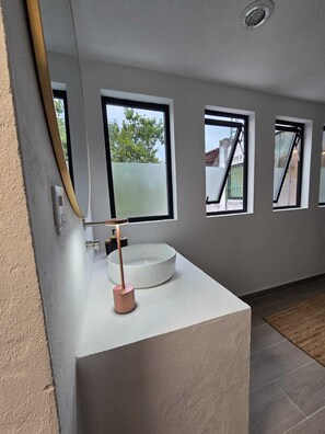 Ein modernes Badezimmer mit großem Fenster, einem weißen Waschbecken und einem Messingarmaturen.