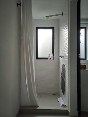 Un baño con ventana, toalla y cortina de ducha.