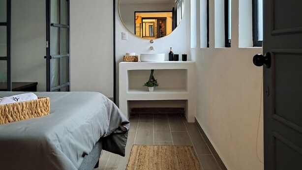 A bedroom with a bed, a bedside table, a mirror, a dresser, and a window. - Casa Puerto Siete8 (Mexico City)