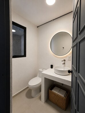 Un baño moderno con inodoro, lavabo y espejo.