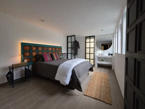 Un dormitorio moderno con una cama, una mesita de noche, un espejo y una lámpara de pared.
