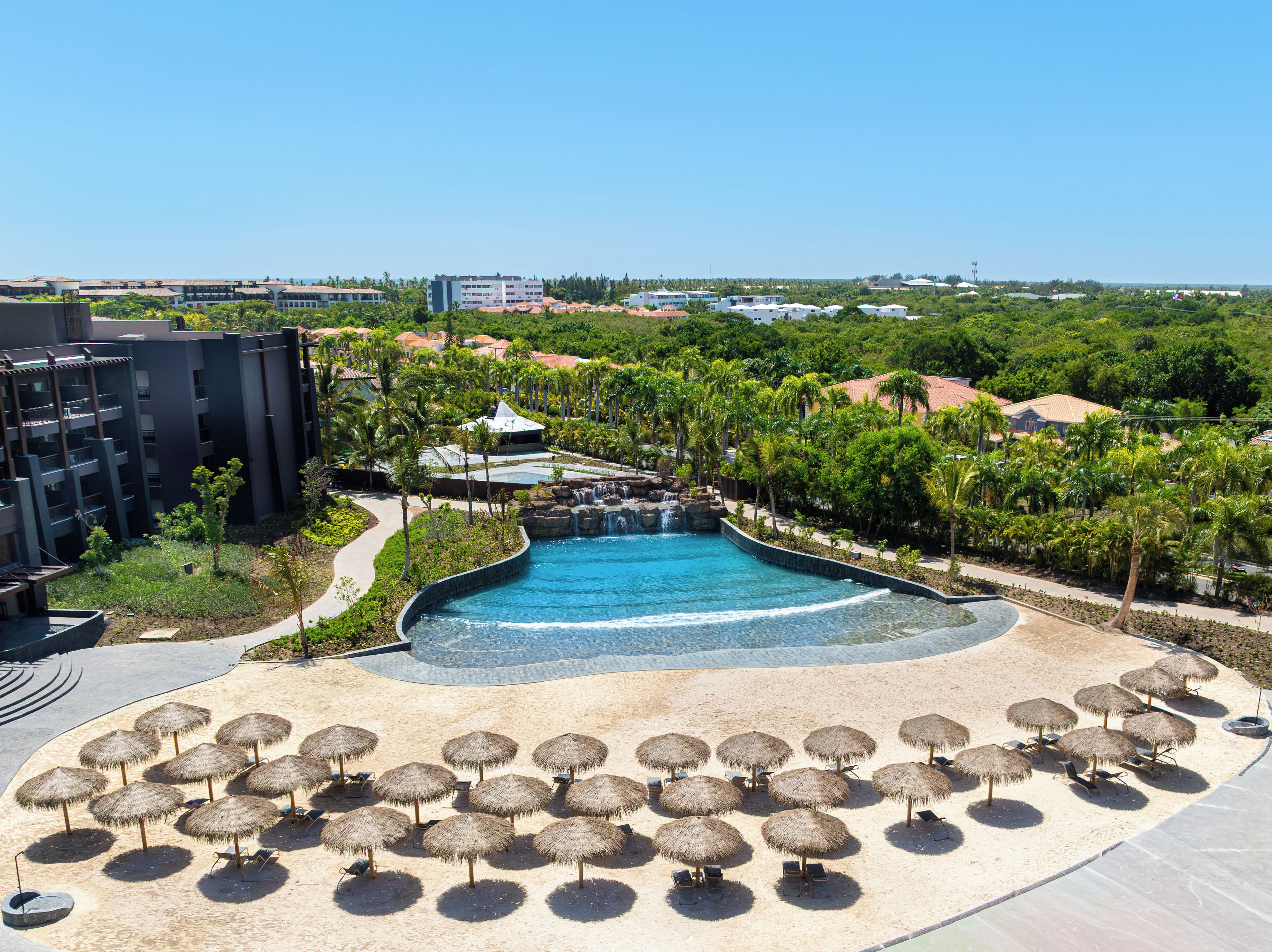 Un complexe hôtelier doté d’une piscine, de chaises longues et de parasols.