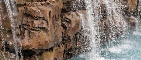 A man and a woman in a pool with a waterfall feature.