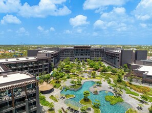 A resort with a central swimming pool, lush landscaping, and modern buildings. - Lopesan Caoba Lagoon Resort, Spa & Casino (Punta Cana)