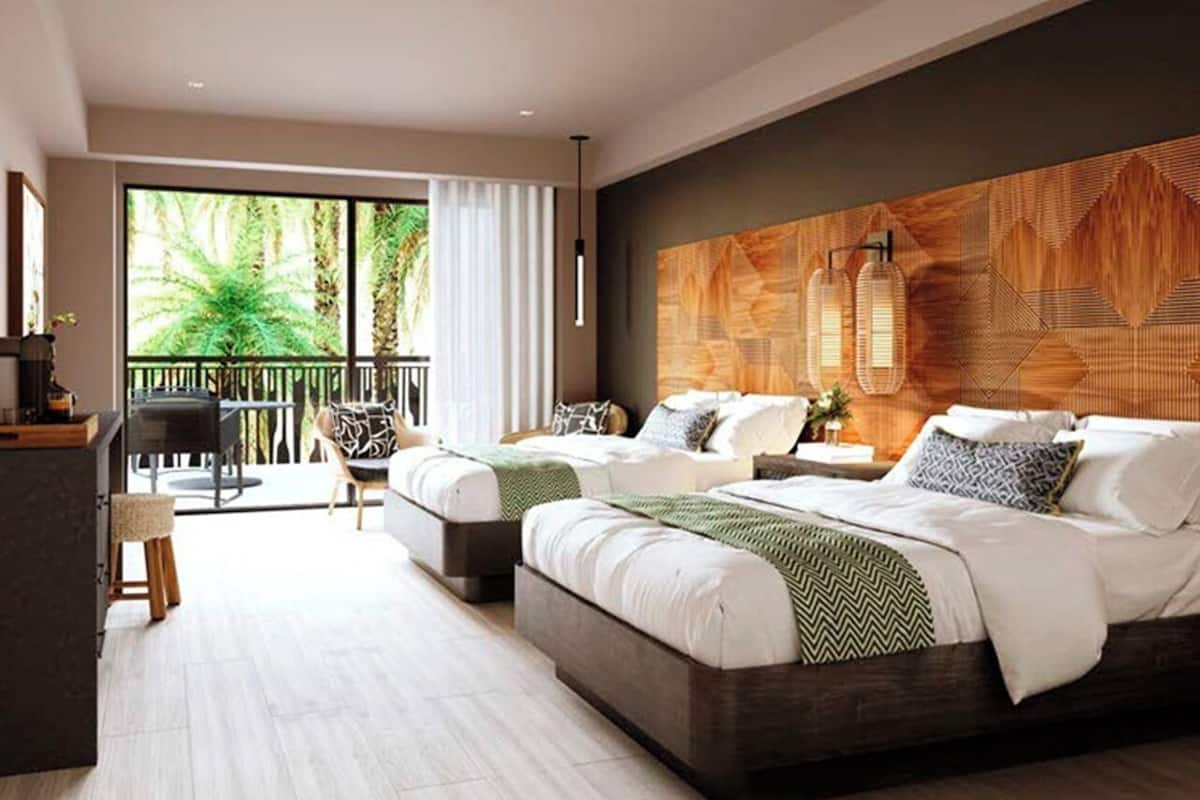 Une chambre d’hôtel moderne avec deux lits, un balcon donnant sur un espace verdoyant et un mur décoratif en bois.