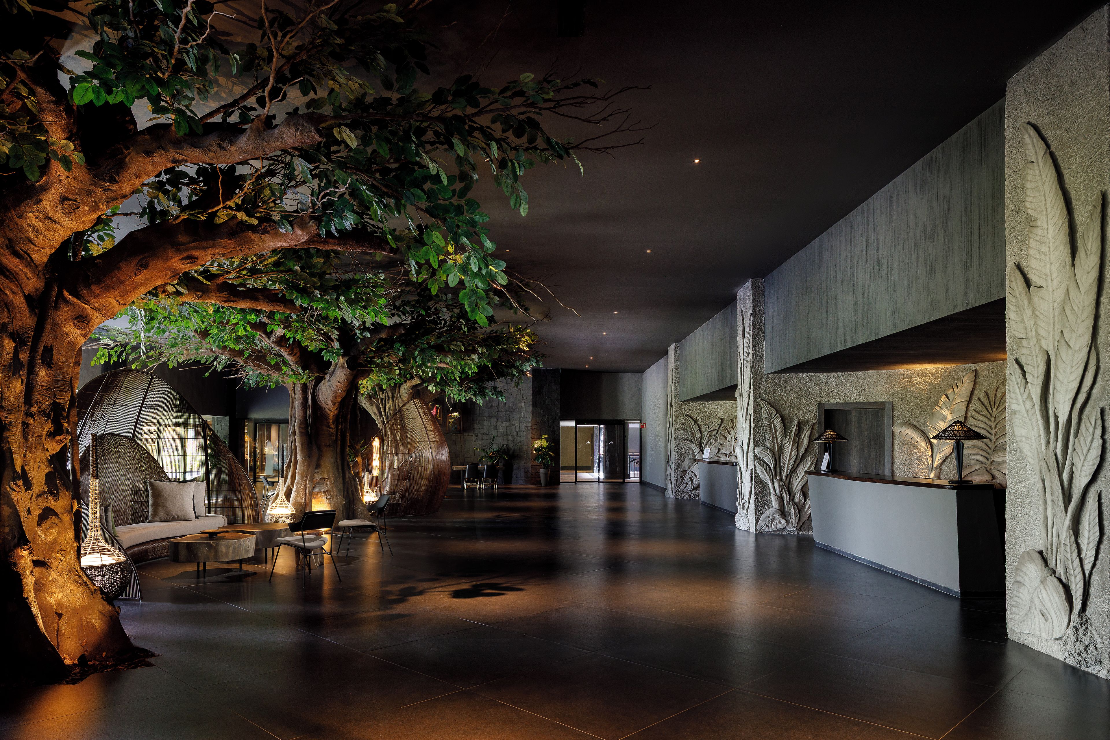 Un'ampia hall con un grande albero artificiale, zone relax e una reception.