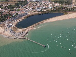 An aerial view of a coastal town with a marina, sandy beach, and a pier extending into the water. - Cottage near the beach with garden - La Tranche-sur-Mer (La Tranche-sur-Mer)