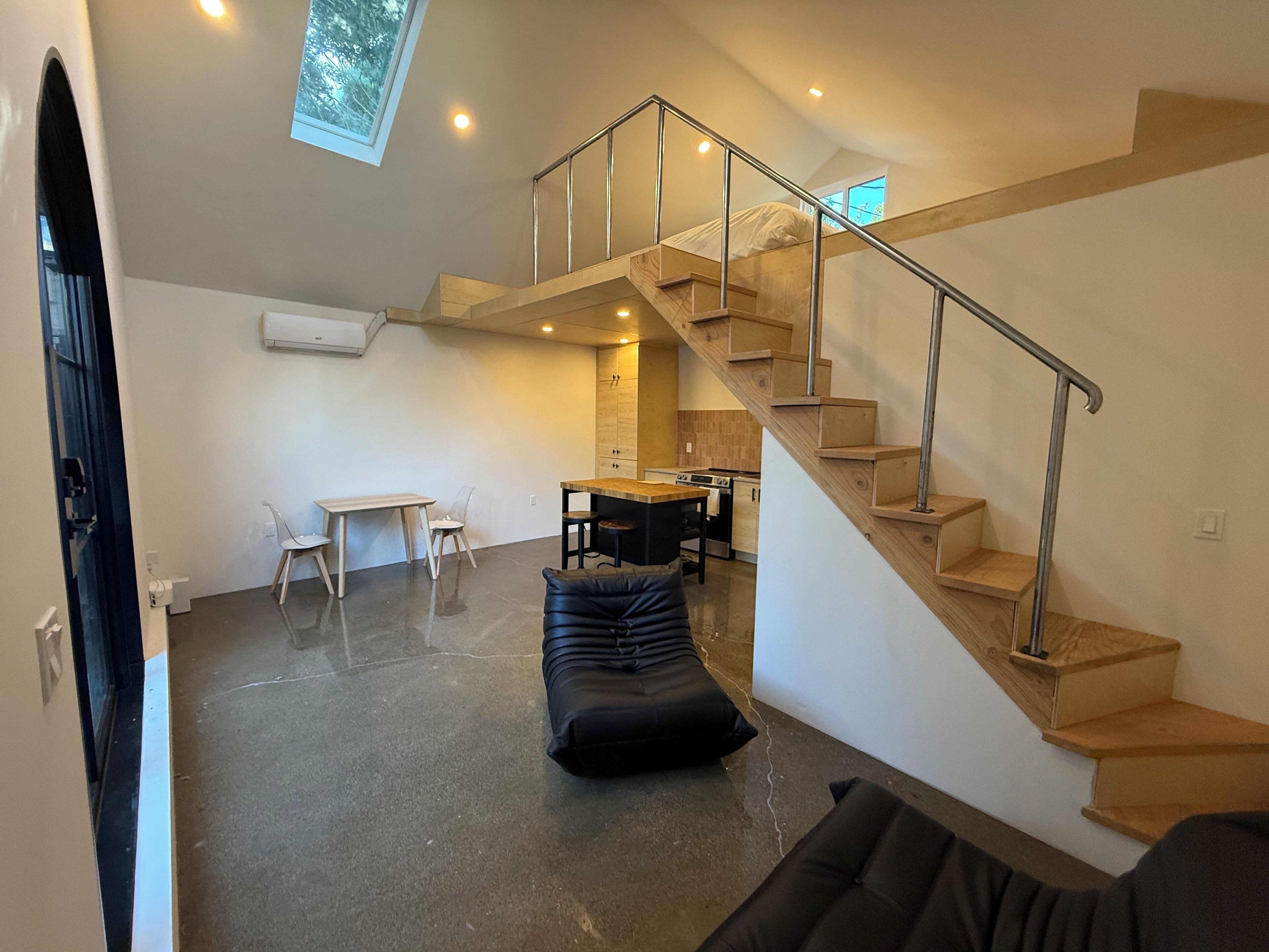 A modern living space with a staircase, a dining area, and a kitchen.