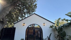 A building with a white exterior, a large arched entrance, and two wall-mounted lights. - Brand New Moderne house with Private Garden Prime LA Location (Los Angeles)