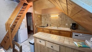 Una cucina compatta con mobili in legno, un lavello a due vasche e un piccolo frigorifero.