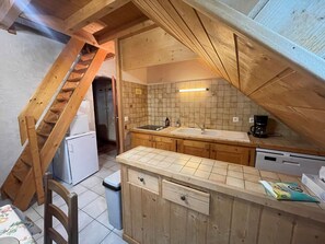 Eine kleine Küche mit Holzausstattung, einer doppelten Spüle und einem Kühlschrank.
