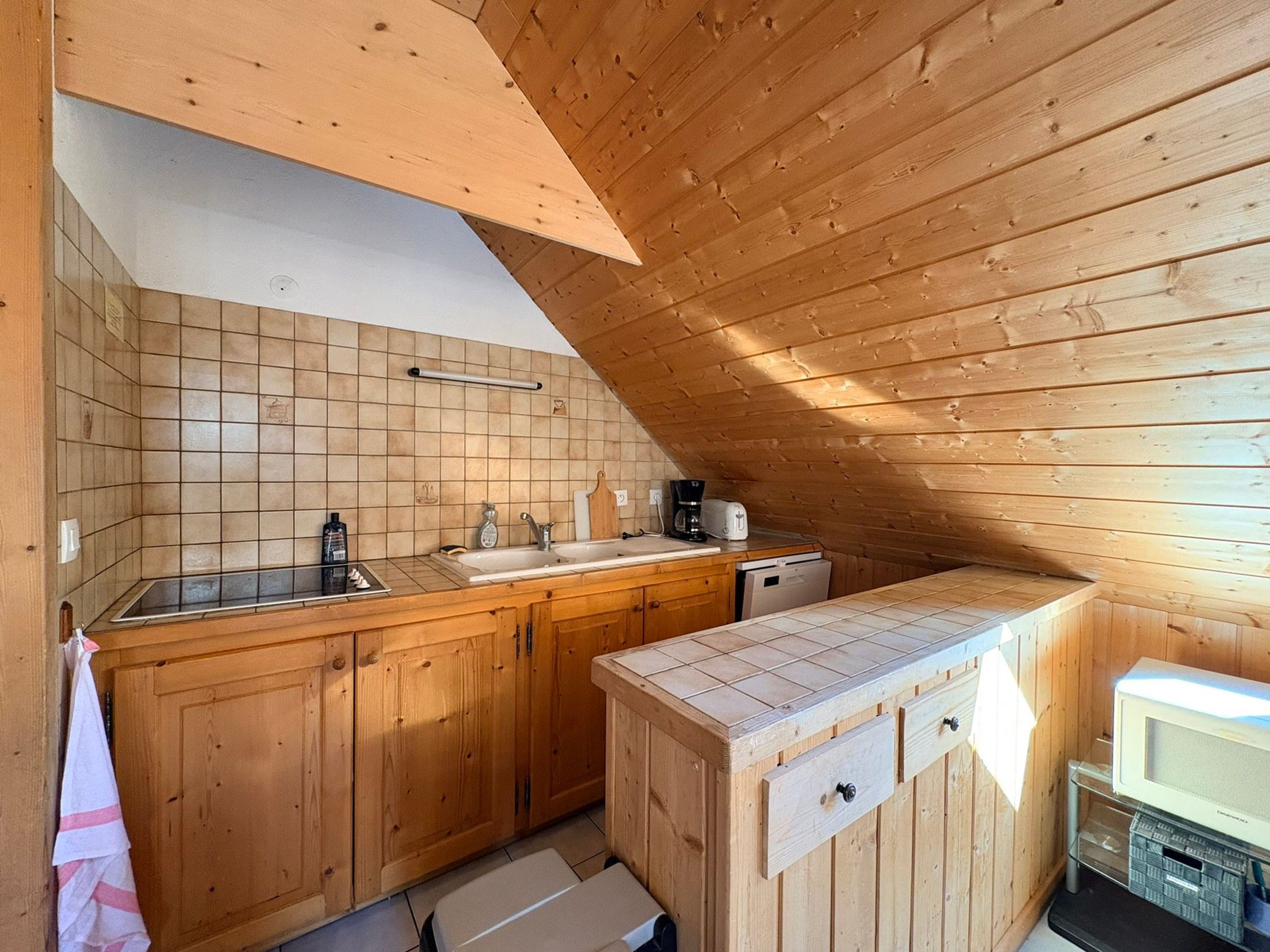 A compact kitchen with wooden cabinets, a sink, and a microwave.