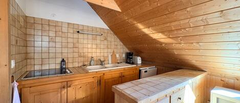 A compact kitchen with wooden cabinets, a sink, and a microwave.