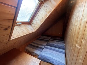 A small attic bedroom with a sloped ceiling, a skylight, and a bed with striped bedding. - Charming 2-room apt for 4 near slopes with ski locker (La Salle-les-Alpes)