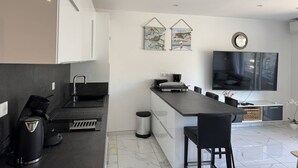 Una cucina moderna con forno integrato, macchina del caffè e un piccolo cestino.