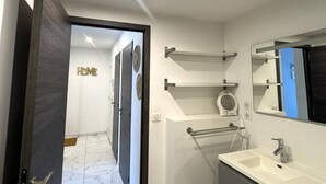 Un bagno moderno con un lavandino bianco, uno specchio e un portasciugamani.