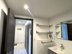 A modern bathroom with a white sink, a mirror, and a towel rack. - Air-conditioned T2, private parking, near the beach (Cavalaire-sur-Mer)