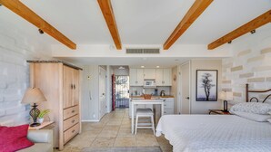 A bedroom with a bed, bedside table, lamp, and a view of the kitchen area. - Hike & Explore Dtwn Tucson! Relaxing Solo Escape (Tucson)