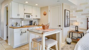 A compact kitchen with white cabinets, a microwave, and a wooden table with a placemat. - Hike & Explore Dtwn Tucson! Relaxing Solo Escape (Tucson)
