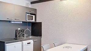 Una cucina compatta con forno a microonde, lavastoviglie e un piccolo tavolo con sedie.
