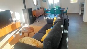 Ein modernes Wohnzimmer mit einer Couch, einem Fernseher und einem Essbereich mit Stühlen und einem Tisch.