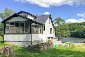 Ein zweistöckiges Haus mit großen Fenstern, einem Steinfundament und Seeblick.
