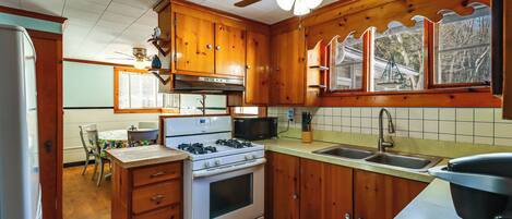 A kitchen with wooden cabinets, a stove, a microwave, and a ceiling fan.