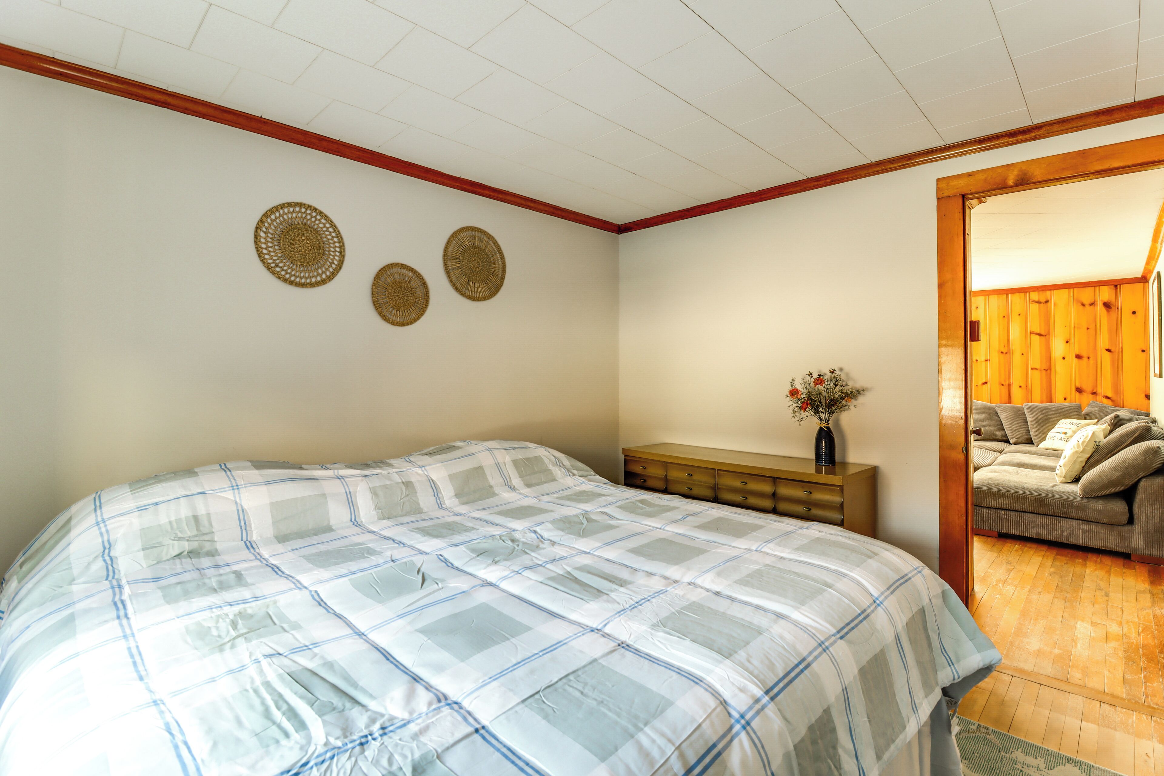 A bedroom with a large bed, a wooden dresser, and a small table with a vase.