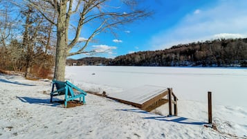Un banc et une structure en bois dans un paysage enneigé, avec des arbres et un ciel dégagé.