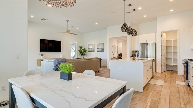 A modern kitchen with white cabinets, a marble island, and a built-in oven. - Hot Tub & Community Perks! Sleek Goodyear Retreat (Goodyear)