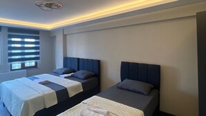 A modern hotel room with two beds, a ceiling fan, and a window with blinds. - rema house (Gemlik)