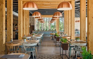 A restaurant with wooden beams, copper pendant lights, and a stone wall in the background. Tables are set with chairs and potted plants. - 2 bedroom stunning (sta)caravan in Vabriga (Vabriga)