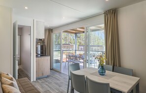 Eine moderne Küche mit Einbauofen, ein Essbereich mit Tisch und Stühlen sowie eine Glastür zu einer Außenpatio.