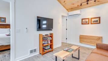 Een moderne woonkamer met een flatscreen televisie, een houten boekenkast en een bruine leren bank.