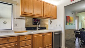 A kitchen with wooden cabinets, a stainless steel dishwasher, and a white countertop. - Pool & Personal Bar! 4 Mi to Downtown Mesa Home (Mesa)
