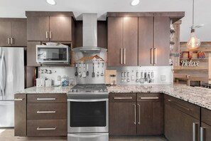 A modern kitchen with dark wood cabinets, stainless steel appliances, and a granite countertop. - Hot Tub Soaks & Foodie Strolls! Berkeley Area Base (Denver)