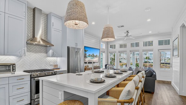 A modern kitchen with white cabinetry, stainless steel appliances, and a large island with bar stools. - Palmilla Resort home with heated pool, golf, beach access, balconies, W/D, AC (Port Aransas)