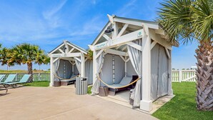 Two beach huts named 'Damselfish' and 'Porroffish' with hammocks, a concrete patio, and a white picket fence in the background. - Palmilla Resort home with heated pool, golf, beach access, balconies, W/D, AC (Port Aransas)