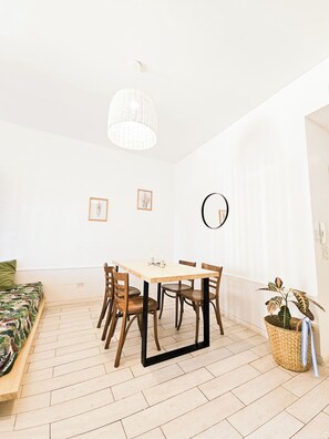 Uma área de refeições com mesa, cadeiras e um lustre.