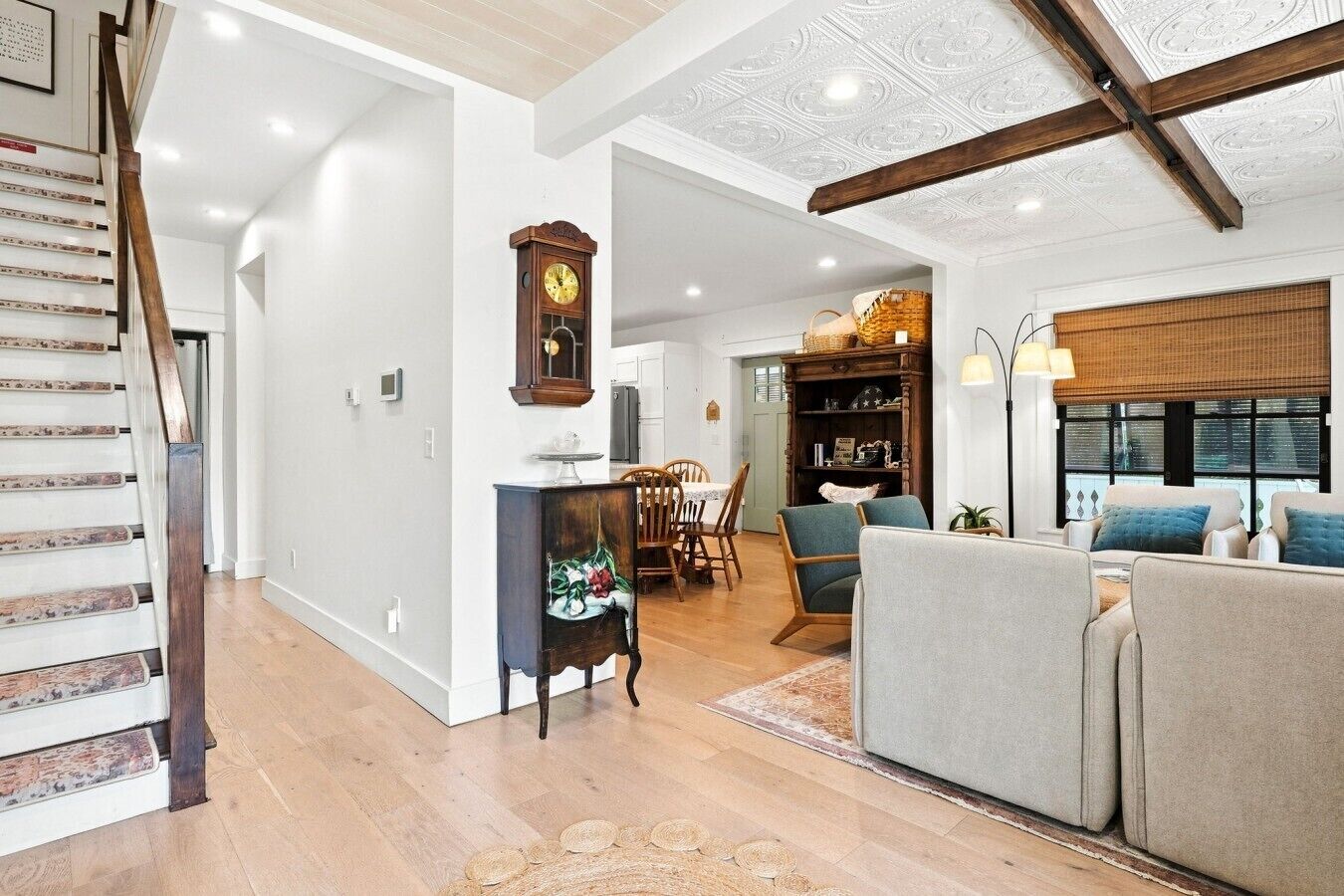 A spacious living area with a staircase, a dining area, and a seating area with a sofa and chairs.