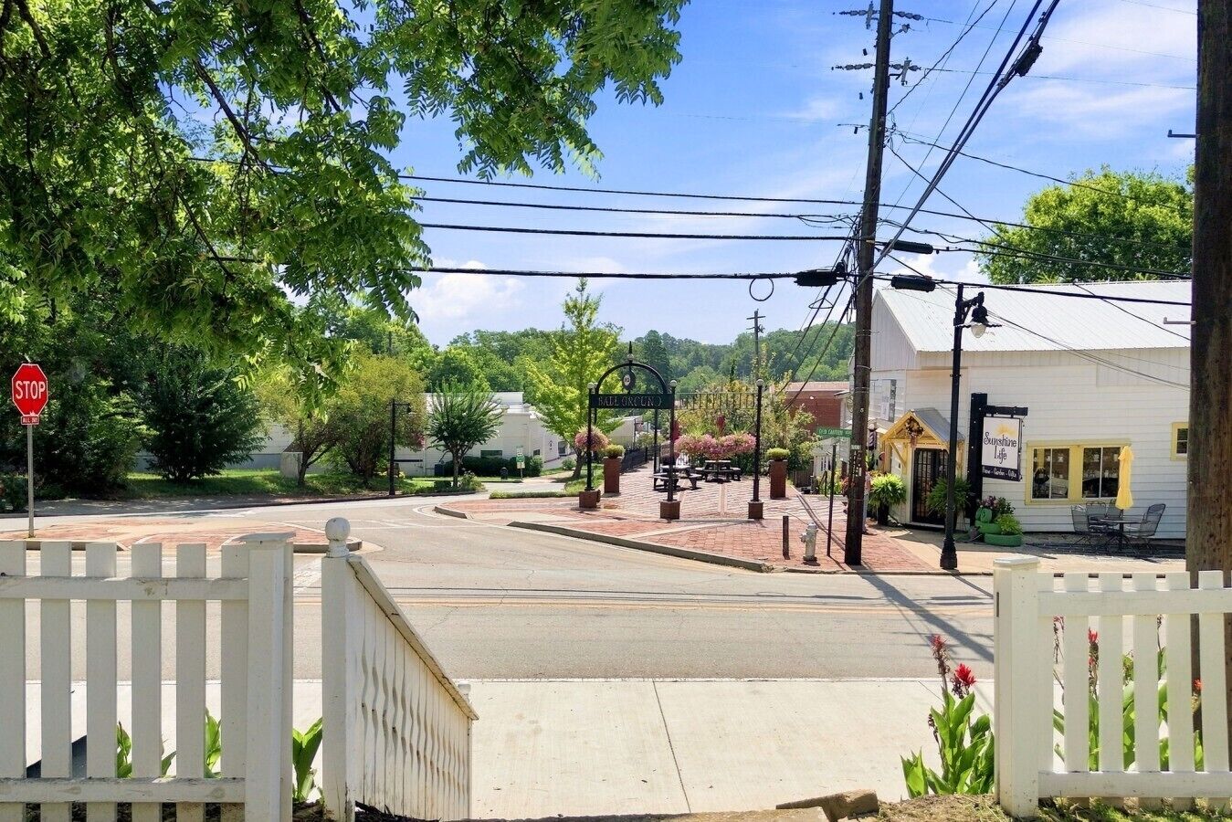 Une vue de rue avec un panneau de signalisation indiquant un arrêt obligatoire, une entrée fermée par un portail et un bâtiment doté d’une terrasse.