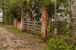 Ein rustikales Backsteinhaus, umgeben von üppigem Grün und Bäumen, mit einem Holzzaun.