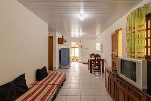 Ein Wohnzimmer mit einer Couch, einem Fernseher und einem Essbereich mit Tisch und Stühlen.
