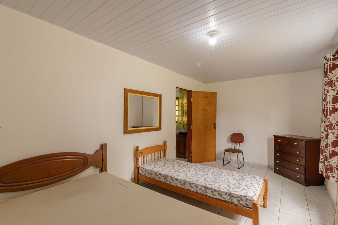 Una camera da letto con un letto di legno, una cassettiera, una sedia e uno specchio.