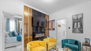 Ein modernes Wohnzimmer mit einer Couch, Sesseln, einem Kamin und Kunstwerken an den Wänden.