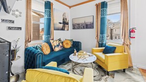 Ein modernes Wohnzimmer mit einem blauen Sofa, gelben Sesseln und einem Kaffeetisch aus Marmor.