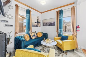 Una sala de estar moderna con un sofá azul, sillones amarillos y una mesa de centro de mármol.