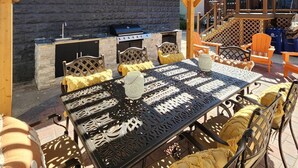 Eine Terrass mit Grill, Sitzgelegenheiten und einem überdachten Bereich mit Holzbalken.