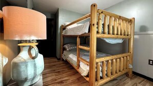 Een stapelbed in een kamer met een houten vloer, een lamp en een vaas.